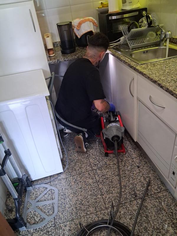 Técnico a desentupir a canalização de uma cozinha com máquina profissional
