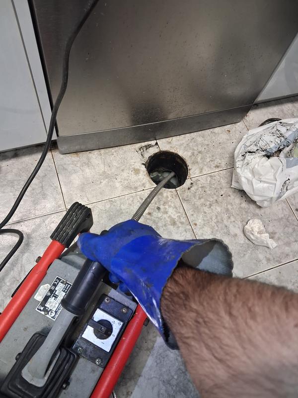 Técnico com luvas a operar a máquina de desentupimento